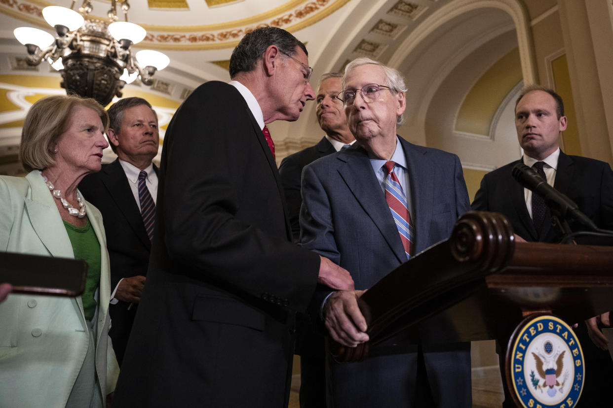 Sen. John Barrasso reaches out to help McConnell after McConnell froze at the microphones during a news conference on July 26.