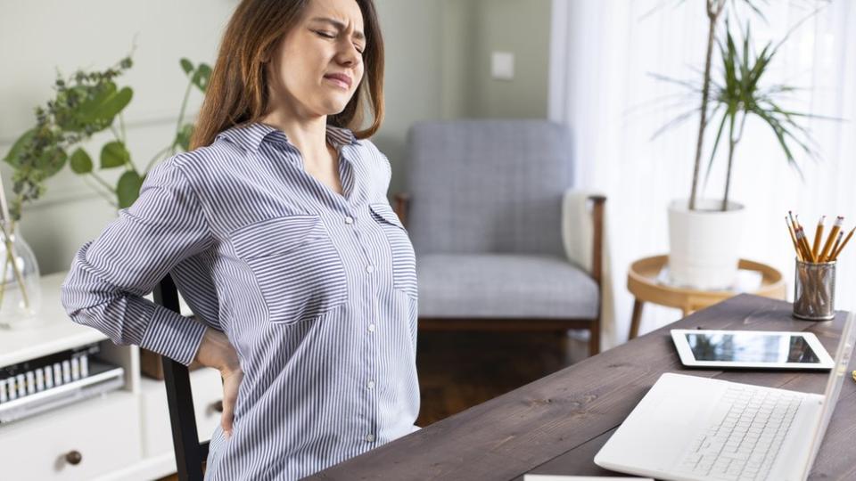 Mujer trabajando desde casa con dolor de espalda.