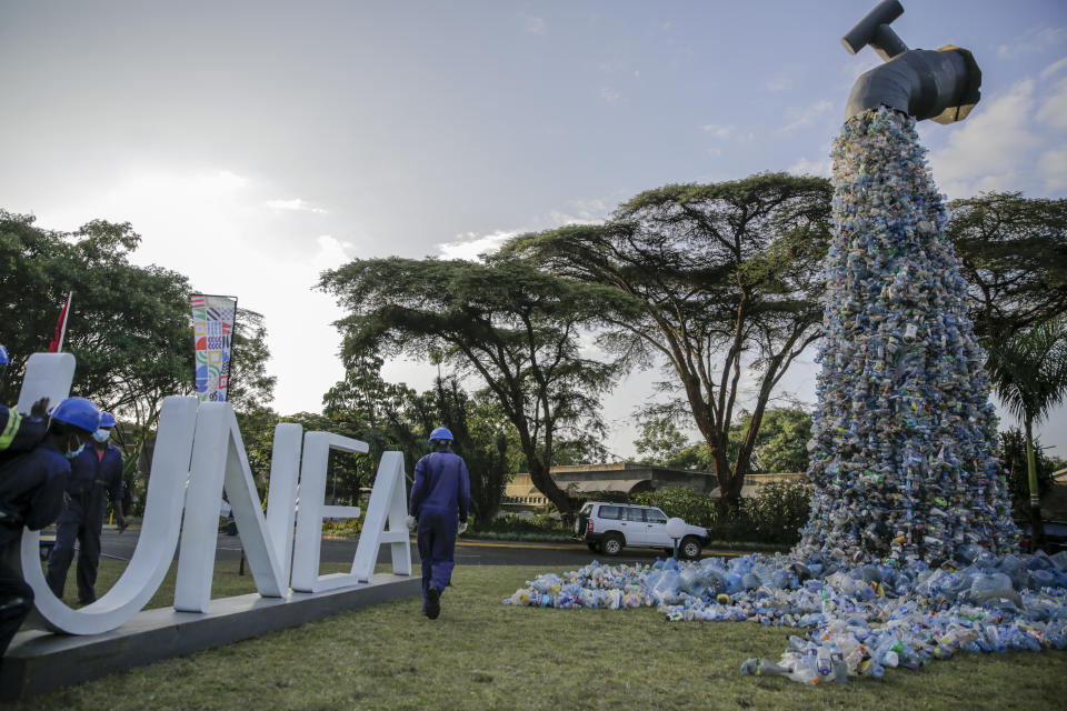 Workers next to a giant art sculpture showing a tap outpouring plastic bottles, each of which was picked up in the neighborhood of Kibera, during the U.N. Environment Assembly (UNEA) held at the U.N. Environment Programme (UNEP) headquarters in Nairobi, Kenya Wednesday, March 2, 2022. Delegates met to discuss a binding international framework to address the growing problem of plastic waste in the world's oceans, rivers and landscape. (AP Photo/Brian Inganga)