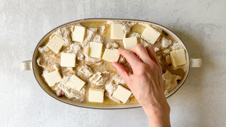 Placing sliced butter on top of almond-rhubarb dump cake