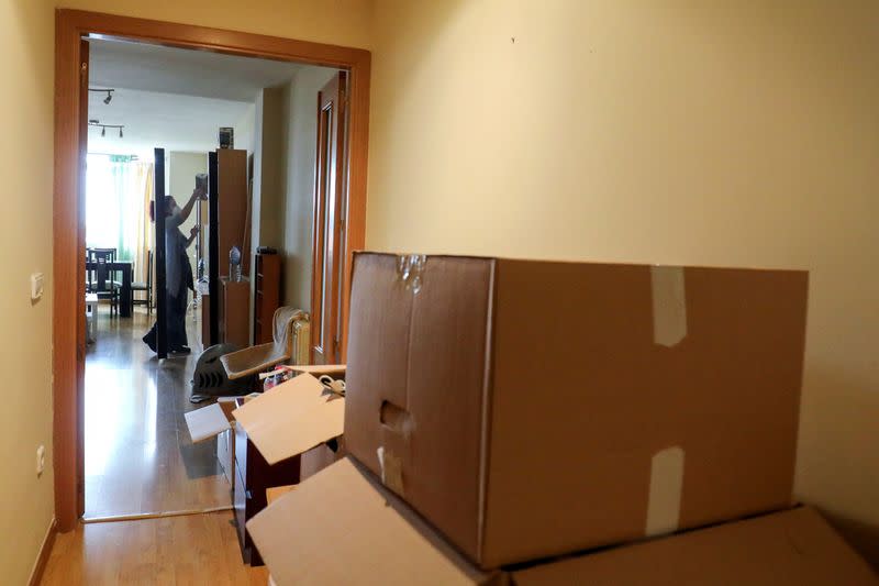 Ines Alcolea places objects at the dining room after unpacking moving boxes in her new rented apartment in Fuensalida