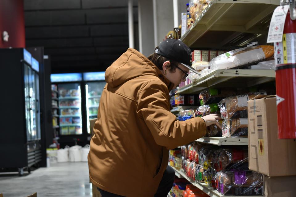 Employee T.J. Owsianowski stocks shelves in East Race Market on Monday, Jan. 8, 2024. Matthews expects a couple of employees at a time to work in the store, open 9 a.m. to 9 p.m.