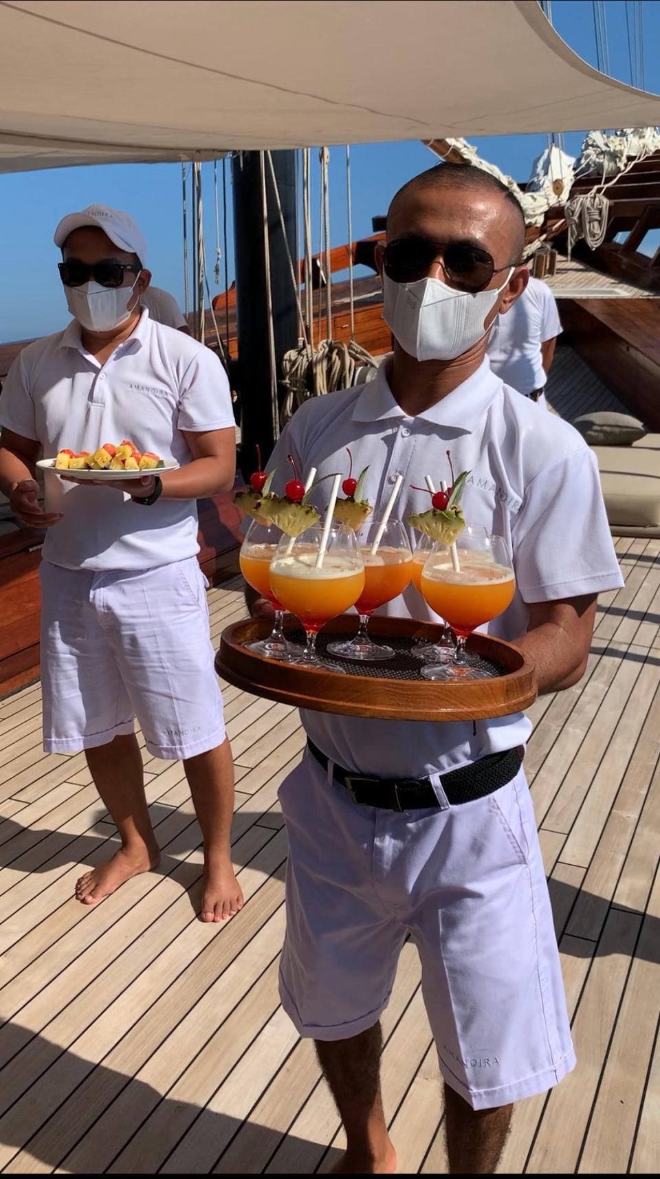 A crew member on board a ship wearing a face mask and serving drinks.