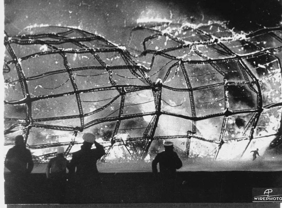 <p>The blazing inferno that was the German airship Hindenburg is reduced to ruins as a survivor, lower right hand corner, runs to safety, May 6, 1937, after it exploded on mooring at Lakehurst Naval Air Station in New Jersey. Rescuers, left and center, rush forward to pull other passenger and crew away from the fiery wreckage. (AP Photo) </p>