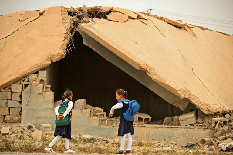 Iraqi pupils walk past a destroyed house in Habash (AFP/AHMAD AL-RUBAYE)