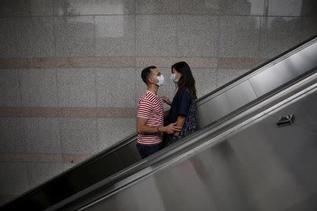 A couple wearing masks to prevent contracting Middle East Respiratory Syndrome (MERS) looks at each other as they ride on an escalator in Seoul, South Korea, June 11, 2015. REUTERS/Kim Hong-Ji