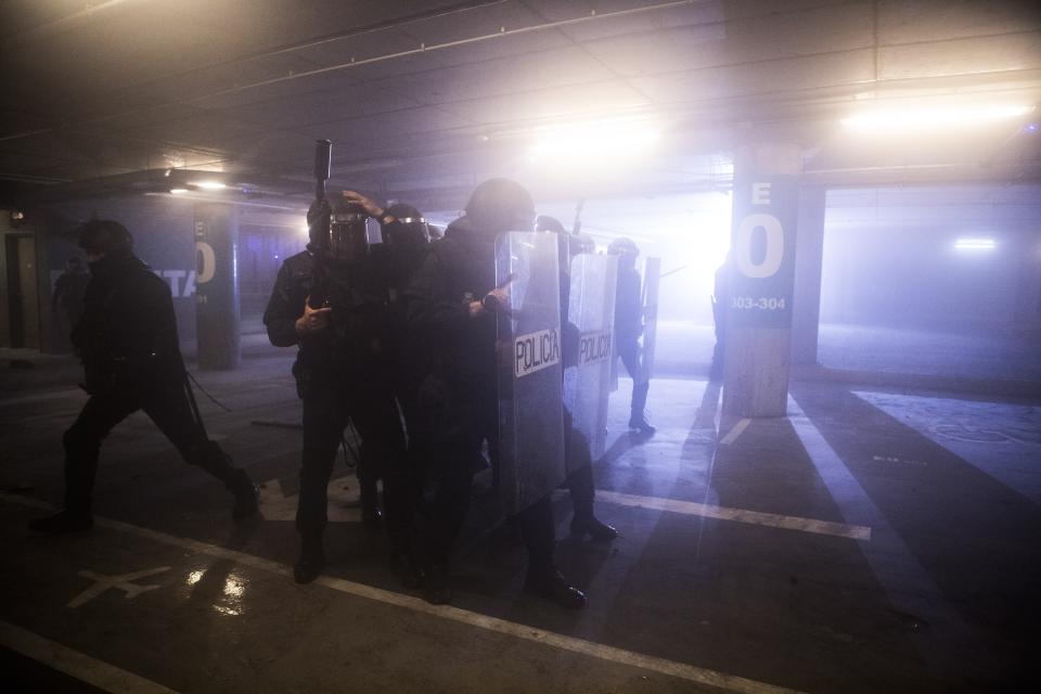 In this Monday, Oct. 14, 2019 photo, Spanish police in action during clashes with pro-independence protesters during a demonstration at El Prat airport, outskirts of Barcelona, Spain. Riot police engaged in a running battle with angry protesters outside Barcelona's airport Monday after Spain's Supreme Court convicted 12 separatist leaders of illegally promoting the wealthy Catalonia region's independence and sentenced nine of them to prison. (AP Photo/Joan Mateu)