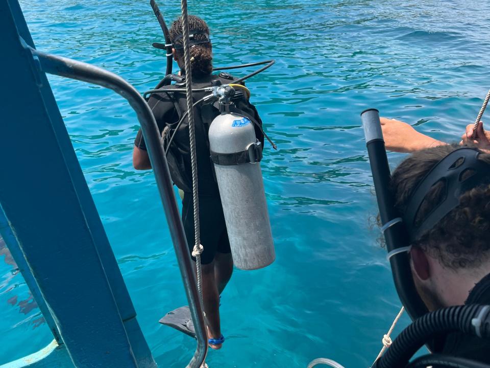 dominique being lowered into the water with scuba gear on to go scuba diving off a boat in Thailand