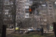 FILE - People look at a burning apartment building after shelling in Mariupol, Ukraine, March 13, 2022. (AP Photo/Evgeniy Maloletka, File)