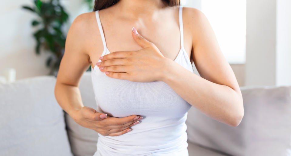 Image of a woman checking breasts for lumps. (Getty Images)