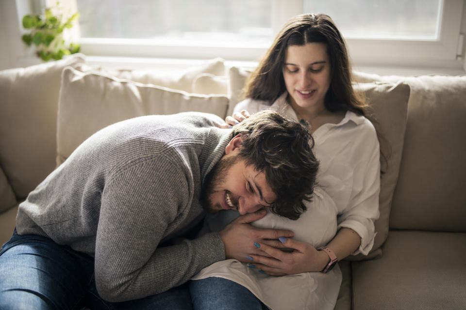 guy putting his head and hear to a pregnant belly