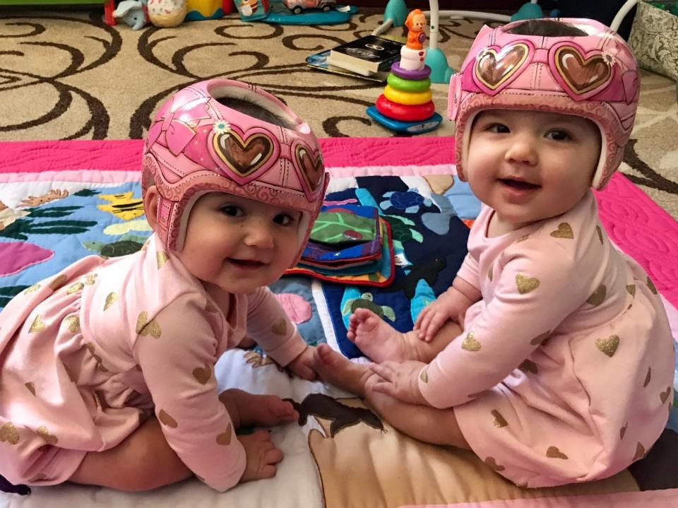 Twin baby girls wearing Lazardo designed pink helmets.