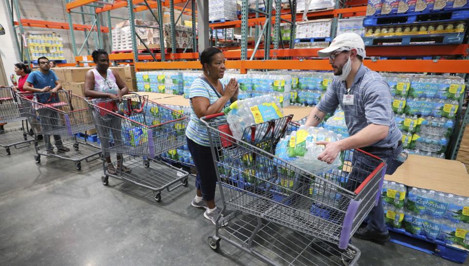 A shopper is grateful to get two cases of bottled water —the limit per customer — at a Costco store in Altamonte Springs, Fla., Friday, Aug. 30, 2019, as central Florida residents prepare for a possible strike by Hurricane Dorian. (Joe Burbank/Orlando Sentinel via AP)