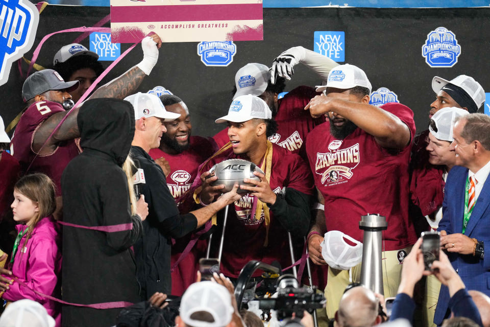 Dec 2, 2023; Charlotte, NC, USA; Florida State Seminoles quarterback Jordan Travis (13) holds the ACC Championship trophy after the game against the Louisville Cardinals at Bank of America Stadium. Mandatory Credit: Jim Dedmon-USA TODAY Sports