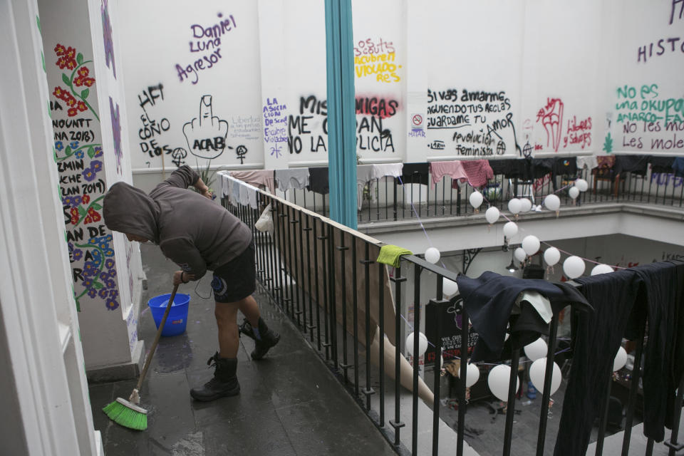 A women’s rights activist cleans at the offices of the Mexican Human Rights Commission (CNDH), which her group has occupied for almost three months, converting it into a refuge for victims of gender violence in Mexico City, Tuesday, Nov. 17, 2020. Feminist activists are occupying the building to demand justice for the victims of sexual abuse, femicide, and other gender violence, and are hosting some women and their children after the government either failed to solve or investigate sexual attacks on their daughters. (AP Photo/Ginnette Riquelme)