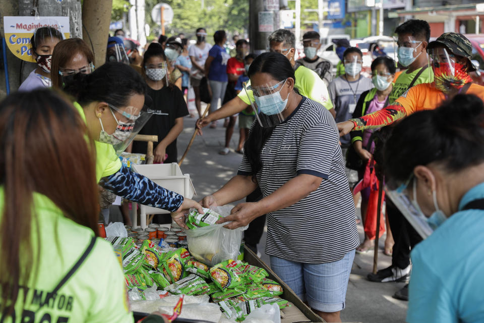 A woman receives free food at a makeshift stall called "Community Pantry" beside a road in Quezon city, Philippines on Monday, April 19, 2021. Donated food and other essential items from residents or volunteers are placed on makeshift stalls for people who need it as many have lost jobs due to quarantine measures set by the government to curb the surge in COVID-19 cases in the country. The "Community Pantry" which started in Maginhawa street has spread to several areas around the metropolitan to support people struggling to make ends meet. (AP Photo/Aaron Favila)