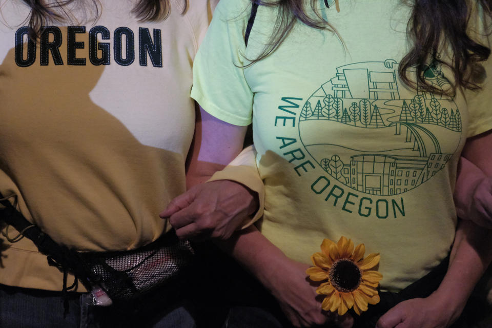 Moms with interlocking arms stand with their backs up against a fence, blocking entry to the federal courthouse, in Portland on July 19 | Alex Milan Tracy—Sipa USA