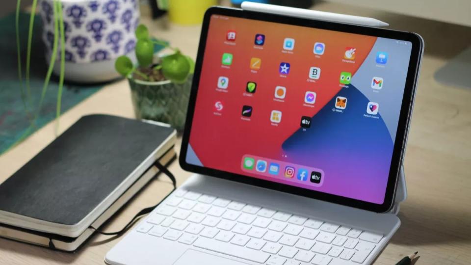 Laptop vs tablet; a photo of an iPad Pro 11-inch on cluttered desk paired with a Magic Keyboard