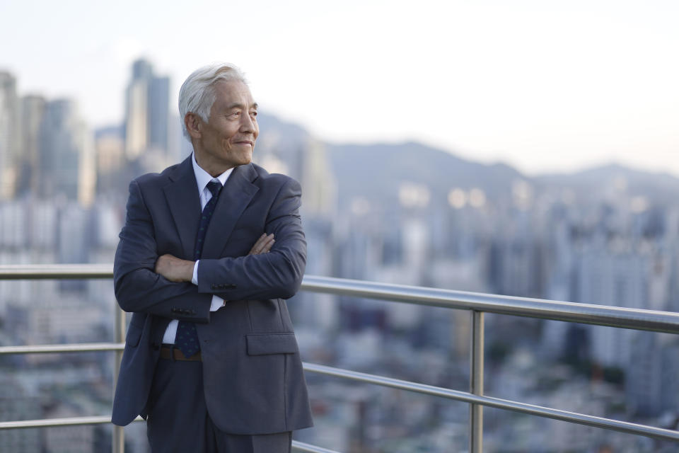 Senior businessman standing with arms crossed on rooftop