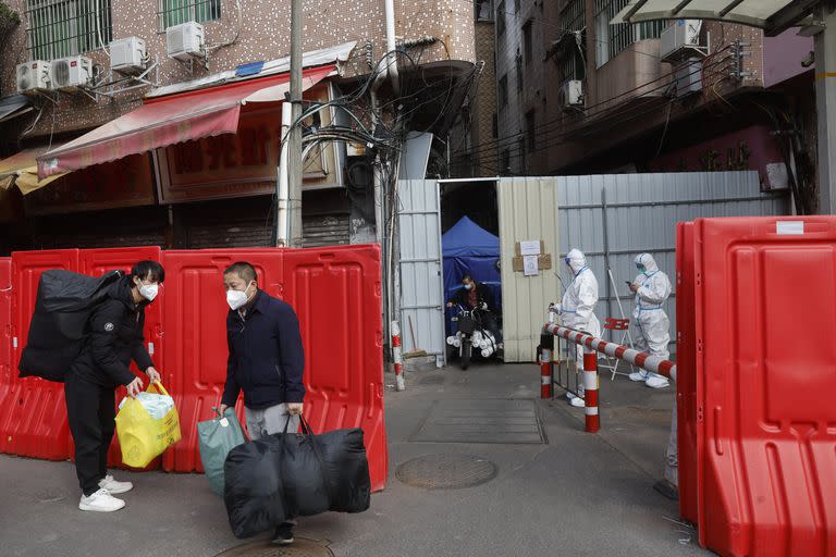 Trabajadores con sus pertenencias abandonan un pueblo con barricadas tras la relajación de las autoridades de las restricciones del COVID-19 en el distrito de Haizhu en Guangzhou, en la provincia de Guangdong, en el sur de China, el viernes 2 de diciembre de 2022.