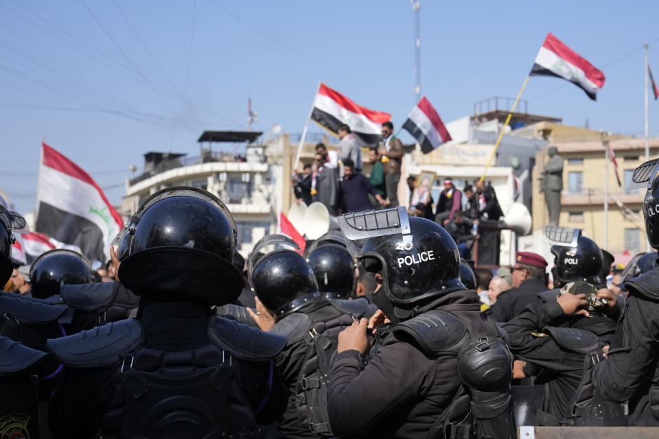 File - Security forces stand guard during a demonstration in front of the Iraqi central bank as currency plummets against the U.S. dollar, in Baghdad, Iraq, Wednesday, Jan. 25, 2023. In recent weeks, Iraq's currency has taken a plunge as a result of newly imposed restrictions on dollar transfers from the U.S., leading to spiking food prices and political unrest. (AP Photo/Hadi Mizban, File)