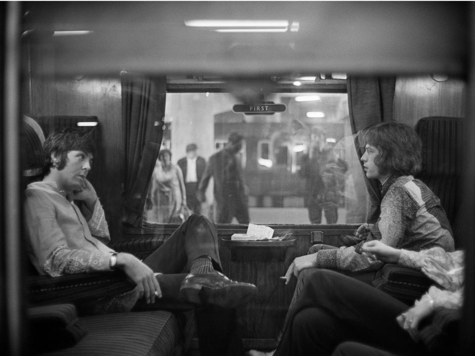 Paul McCartney of the Beatles and Mick Jagger of the Rolling Stones sit opposite each other on a train at Euston Station in 1967.