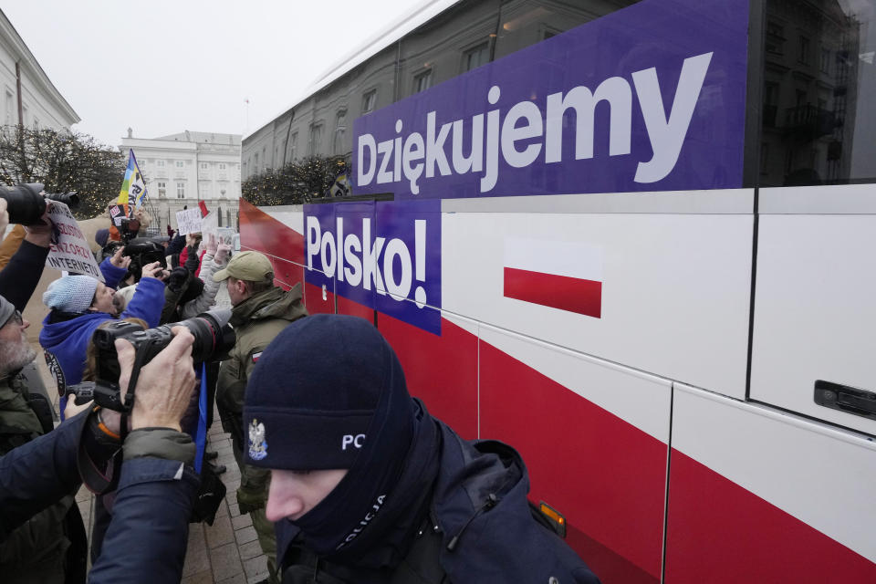 People cheer as a bus carrying Polish Prime Minister Donald Tusk and his ministers leave heading to the presidential palace in Warsaw, Poland, Wednesday Dec. 13, 2023. The swearing-in ceremony marked the end of eight tumultuous years of rule by a national conservative party, Law and Justice, and the ascent of Tusk's pro-European Union administration, which vows to respect constitutional norms and be a steady Western ally and a strong European leader. The writing on bus reads: "We thank you, Poland!" (AP Photo/Czarek Sokolowski)