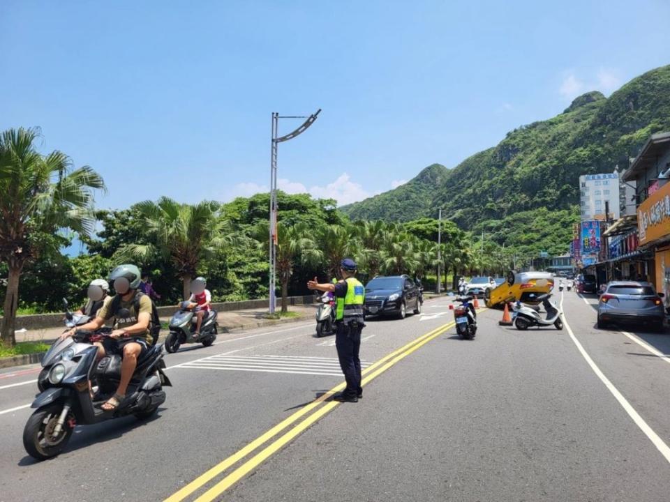 一輛計程車在北寧路段意外擦撞路邊違規停放的轎車，因而翻覆在路中央，員警在炎熱的太陽下疏導交通。（記者張上耕翻攝）