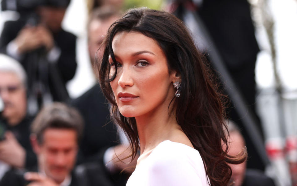 Bella Hadid posing with hair down and diamond earrings at an event