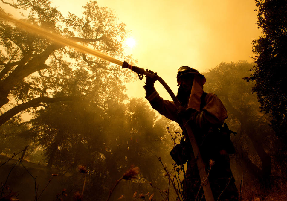 <p>Napa County firefighter Jason Sheumann sprays water on a home as he battles flames from a wildfire Monday, Oct. 9, 2017, in Napa, Calif. (Photo: Rich Pedroncelli/AP) </p>