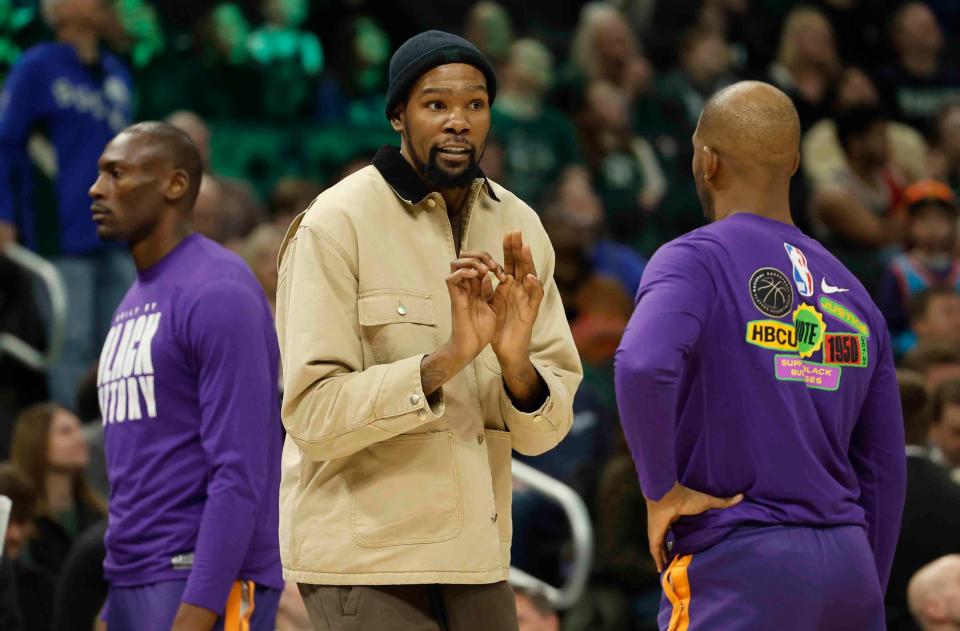 Phoenix Suns' Kevin Durant, middle, talks with teammate Chris Paul during the first half of an NBA basketball game against the Milwaukee Bucks Sunday, Feb. 26, 2023, in Milwaukee. (AP Photo/Jeffrey Phelps)