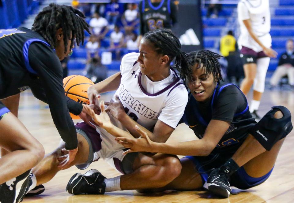 Caravel's Cherish Bryant fights for a loose ball between A.I. du Pont's Sydney Hilliard (left) and Laila Selby-Blaylock in the first half a DIAA state tournament semifinal at the Bob Carpenter Center, Wednesday, March 6, 2024.