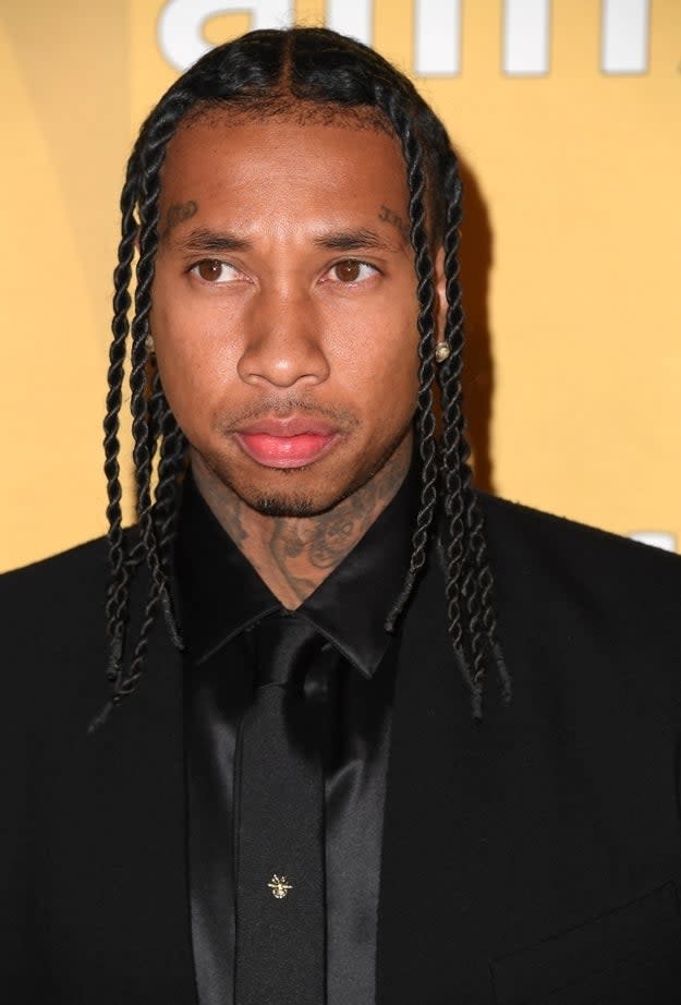 Tyga in a black suit with braided hair at a media event