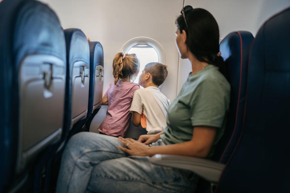 <p>Getty Images</p> Mom sits alone on plane with two kids.