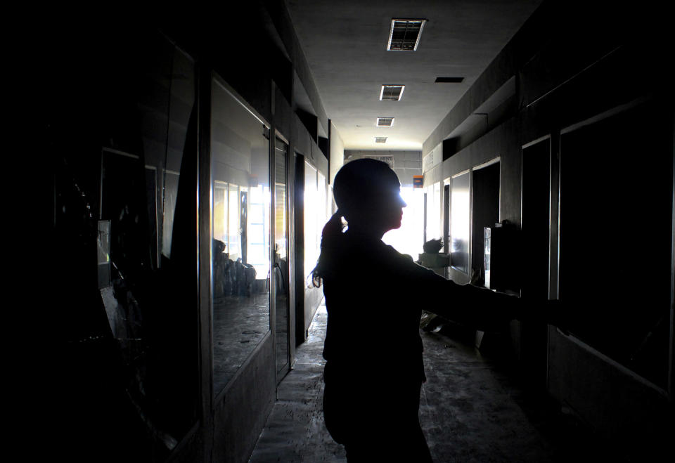 A mall employe inspects stores one day after the mall was looted, in Maracaibo, Venezuela, Wednesday, March 13, 2019. Venezuela's largest private food supplier says massive looting and vandalism occurred at four facilities in the city of Maracaibo during nationwide power outages, complicating efforts to distribute food and drinks to people in the area. (AP Photo/Henry Chirinos)