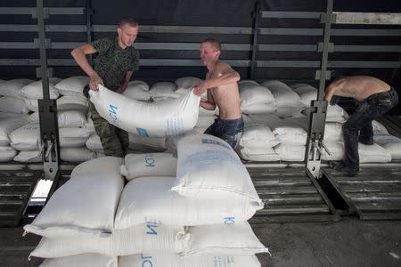 People lift up sacks which are part of a Russian convoy carrying humanitarian aid in Donetsk, eastern Ukraine, September 20, 2014. REUTERS/Marko Djurica