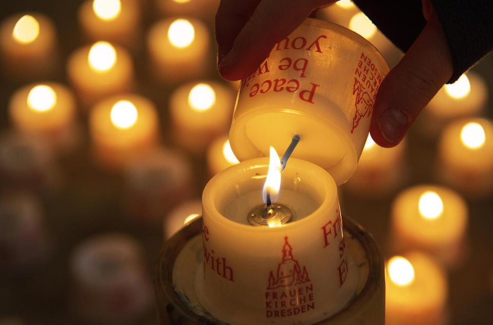 A child lights a candle in the Frauenkirche cathedral (Church of Our Lady) in Dresden, Germany, Tuesday, Feb. 11, 2020 two days before the 75th anniversary of the Allied bombing of Dresden during WWII. British and U.S. bombers on Feb. 13-14, 1945 destroyed Dresden's centuries-old baroque city center. (AP Photo/Jens Meyer)