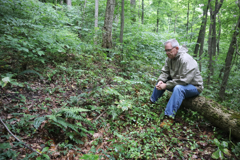 Ed Evans, Democratic West Virginia delegate and retired public school teacher, sits beside a sunken grave in the unmarked cemetery where more than 80 coal miners killed in the 1912 Jed Coal and Coke Company disaster are buried in Havaco, W.Va., on June 7, 2022. (AP Photo/Leah Willingham)