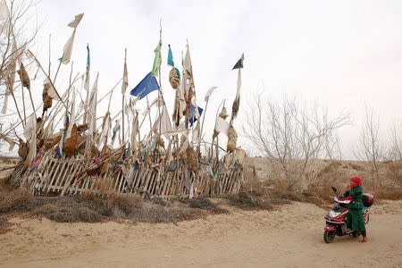 A woman prays at a grave near the tomb of Imam Asim in the Taklamakan Desert outside the village of Jiya near Hotan, Xinjiang Uighur Autonomous Region, China, March 21, 2017. REUTERS/Thomas Peter