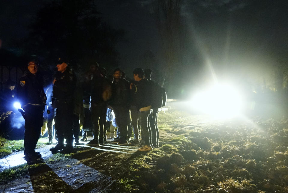 In this photo taken Saturday, Nov. 9, 2019, Bosnian border police officers guard migrants after making the illegal crossing from Serbia by the Drina river, the natural border between Bosnia and Serbia, near eastern Bosnian town of Zvornik, Bosnia. Bosnian border police are warning they cannot contain migratory pressures along the country's eastern border with Serbia, warning the situation could easily escalate and put in danger the overall stability of their politically fragile nation. (AP Photo/Eldar Emric)