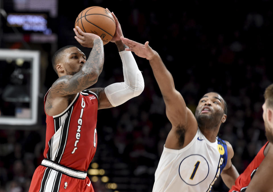 Portland Trail Blazers guard Damian Lillard, left, shoots the ball over Indiana Pacers forward T.J. Warren, right, during the second half of an NBA basketball game in Portland, Ore., Sunday, Jan. 26, 2020. Lillard scored 50 points as the Blazers won 139-129. (AP Photo/Steve Dykes)