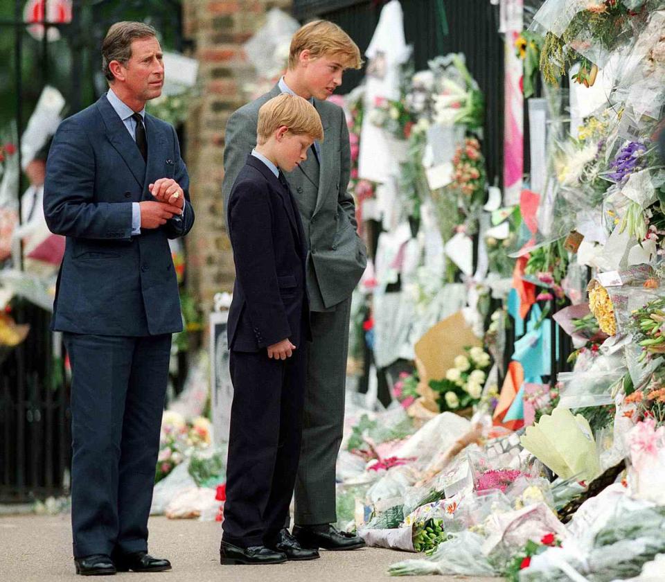 The Prince of Wales, Prince William and Prince Harry look at floral tributes to Diana, Princess of Wales outside Kensington Palace on September 5, 1997 in London, England