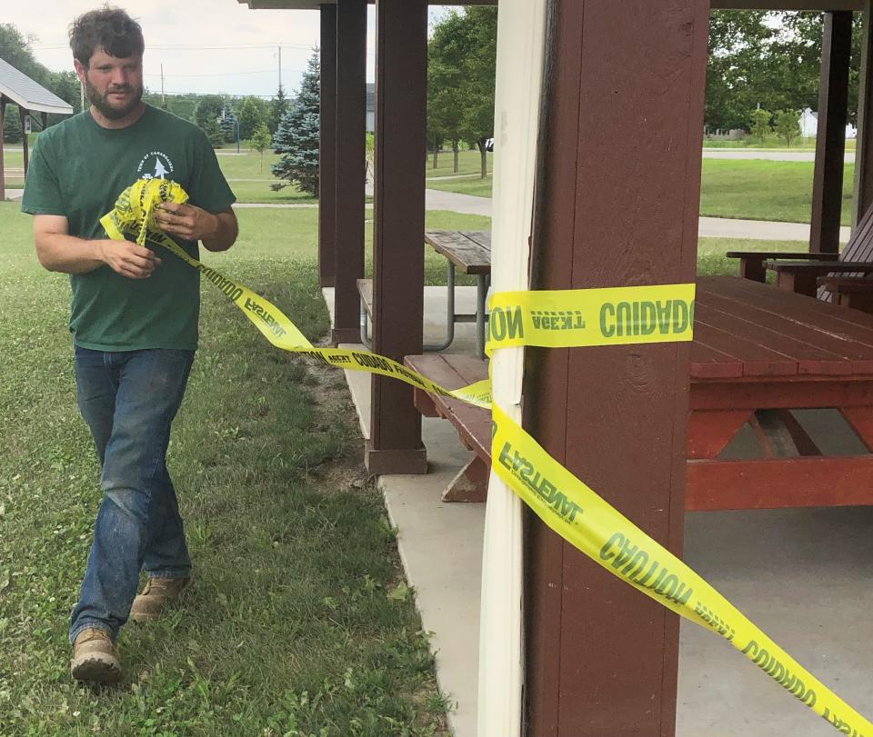 Parks worker Andy Corino removes the yellow tape from a building at Richard P. Outhouse Memorial Park in the town of Canandaigua.