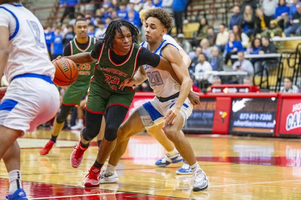 Lawrence North High School junior Azavier Robinson (23) drives the ball into the defense of Franklin Central High School senior Valen Mosley (20) during the second half of a Boysâ€™ Marion County Basketball Tournament championship game, Saturday, Jan. 13, 2024, at Southport High School. Lawrence North won, 78-53.