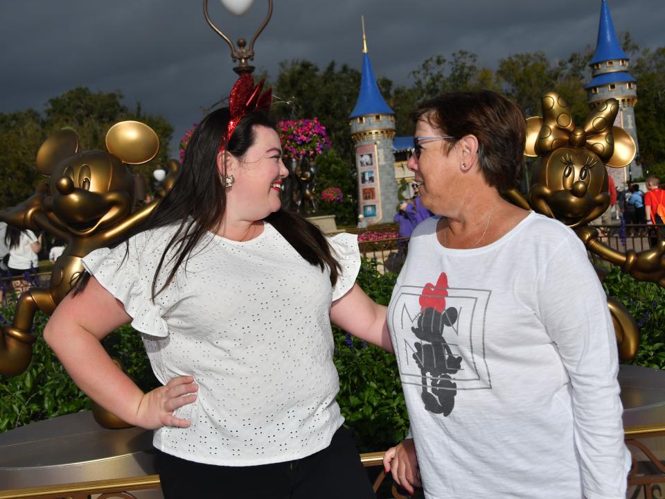 megan and her mom taking photos with mickey and minnie statues at magic kingdom