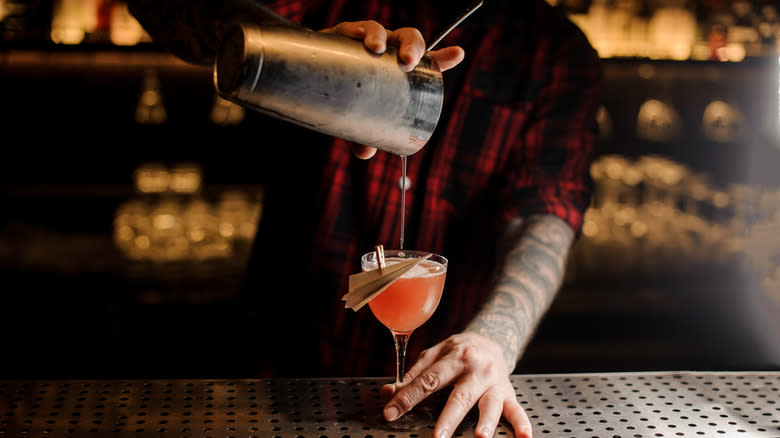 A bartender pouring a Paper Plane cocktail