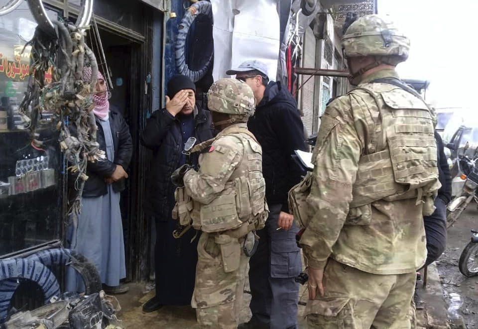 This photo released on the Facebook page of the Military Council of Manbij City, shows U.S. troops based around the Syrian town of Manbij speaking with residents, in northern Syria, Sunday, Dec. 23, 2018. (The Military Council of Manbij City via AP)