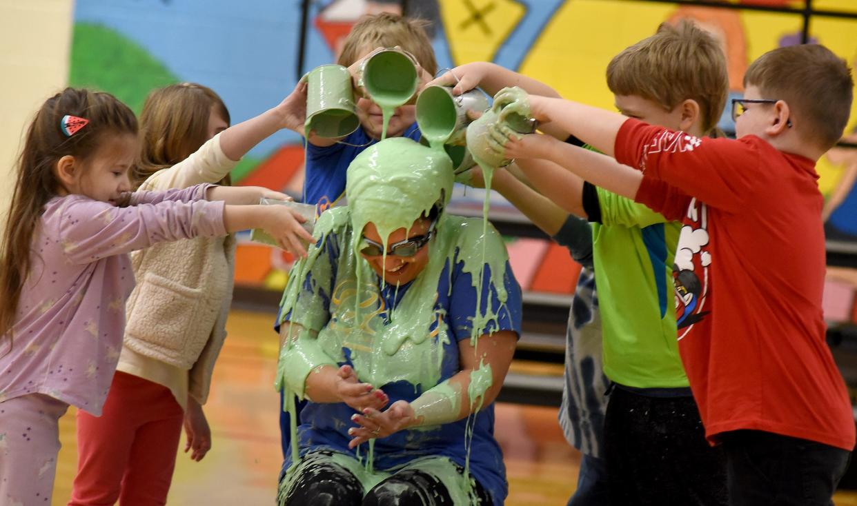 Kindergartners CeCe Bausman and Camila Perna (left) and first graders Eric LaMasters (behind), Alex Blanchett and Aiden Griffith take their turns Friday dumping slime onto Sodt Elementary School Principal Tara Roe.