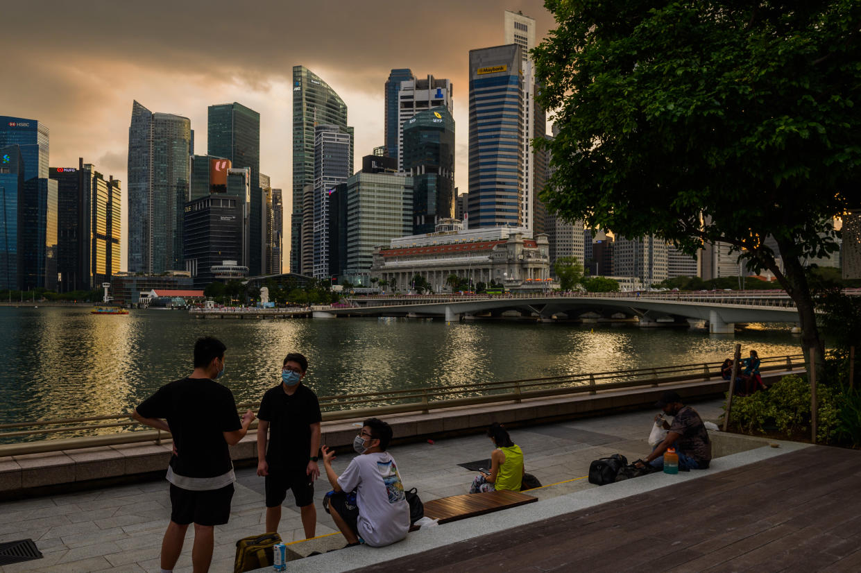 People relax along the waterfront of the Marina Bay area of Singapore with the central business district skyline in the background, in Singapore, Friday, 19 November 2021. (Photo by Joseph Nair/NurPhoto via Getty Images)