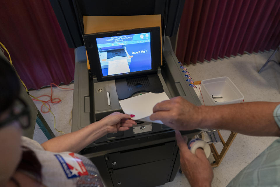 Polling judge Frank Kosek, right, Elaine Rhone, left, guide her ballot into a voting machine during the Pennsylvania primary election, at Mont Alto United Methodist Church in Alto, Pa., Tuesday, May 17, 2022. (AP Photo/ Carolyn Kaster)